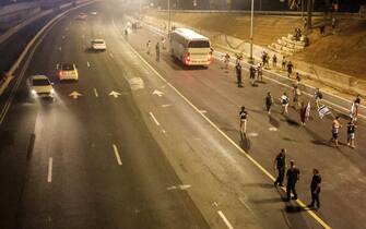 Israeli policemen (C) stand by as demonstrators walk on the side of an empty highway during a protest rally against the Israeli government's judicial reform plan in Tel Aviv on July 24, 2023. Israeli lawmakers on July 24 approved a key clause of a controversial judicial reform plan that aims to curb the powers of the Supreme Court in striking down government decisions. (Photo by JACK GUEZ / AFP) (Photo by JACK GUEZ/AFP via Getty Images)