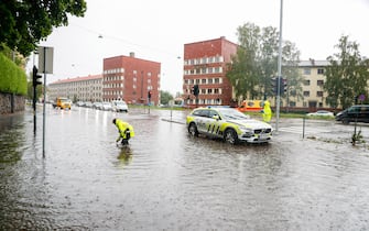 A police officer checks the drain in a flooded street on August 7, 2023 in Oslo, Norway, as storm Hans has been categorized as red weather warning in south-east Norway.  (Photo by Frederik Ringnes / NTB / AFP) / Norway OUT (Photo by FREDERIK RINGNES/NTB/AFP via Getty Images)