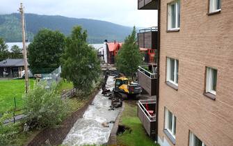 An excavator clears debris from a canal after the Susa River running through Are, northern Sweden, overflowed following heavy rainfall due to extreme weather 'Hans' on August 8, 2023. Large amounts of water an soil have rushed through the village causing damage to properties and roads.  (Photo by Johan Axelsson / TT News Agency / AFP) / Sweden OUT (Photo by JOHAN AXELSSON/TT News Agency/AFP via Getty Images)