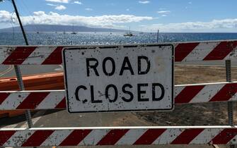 epa10802238 A sign reads 'Road Closed' in Lahaina, Hawaii, USA, 15 August 2023. At least 99 people were killed in the Lahaina wildfire that burnt in Maui, which is considered the largest natural disaster in Hawaii's state history.  EPA/ETIENNE LAURENT