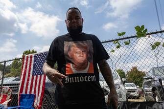 TOPSHOT - A supporter of former President Donald Trump wears a shirt proclaiming his innocence while waiting for him to arrive outside the Fulton County Jail on August 24, 2023, in Atlanta, Georgia. Former US President Donald Trump and 18 others were given until August 25, 2023 to surrender at the courthouse after being indicted on 41 counts related to their efforts to overturn the 2020 US Presidential election. (Photo by Christian Monterrosa / AFP) (Photo by CHRISTIAN MONTERROSA/AFP via Getty Images)