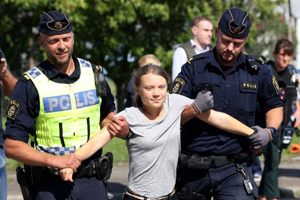 TOPSHOT - Climate activist Greta Thunberg is carried away by police officers after she took part in a new climate action in Oljehamnen in Malmo, Sweden on July 24, 2023, shortly after the city's district court convicted and sentenced her to a fine for disobeying police at a rally last month during a climate action in the Norra hamnen neighbourhood of Malmo. Thunberg was fined on Monday for disobeying police at a rally last month, but said she acted out of necessity due to the climate crisis. (Photo by Andreas HILLERGREN / TT News Agency / AFP) / Sweden OUT (Photo by ANDREAS HILLERGREN/TT News Agency/AFP via Getty Images)