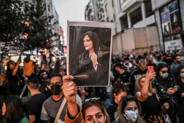 TOPSHOT - A protester holds a portrait of Mahsa Amini  during a demonstration in support of Amini, a young Iranian woman who died after being arrested in Tehran by the Islamic Republic's morality police, on Istiklal avenue in Istanbul on September 20, 2022. - Amini, 22, was on a visit with her family to the Iranian capital when she was detained on September 13 by the police unit responsible for enforcing Iran's strict dress code for women, including the wearing of the headscarf in public. She was declared dead on September 16 by state television after having spent three days in a coma. (Photo by Ozan KOSE / AFP) (Photo by OZAN KOSE/AFP via Getty Images)