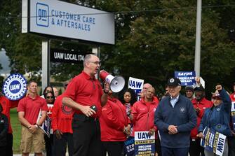 United Auto Workers (UAW) President, Shawn Fain addresses picketing UAW members at a General Motors Service Parts Operations plant as US President Joe Biden listens in Belleville, Michigan, on September 26, 2023, as US President Joe Biden joined the workers.  Some 5,600 members of the UAW walked out of 38 US parts and distribution centers at General Motors and Stellantis at noon September 22, 2023, adding to last week's dramatic worker walkout.  According to the White House, Biden is the first sitting president to join a picket line.  (Photo by Jim WATSON / AFP) (Photo by JIM WATSON/AFP via Getty Images)