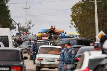 Armenian police officers walks near refugees as they queue in vehicles near the border town of Kornidzor, arriving from Nagorno-Karabakh, on September 26, 2023. Hundreds of vehicles were heading to Armenia from Nagorno-Karabakh on September 26, 2023, following Azerbaijan's lightning offensive against the separatist enclave, an AFP team at the scene said. (Photo by Alain JOCARD / AFP) (Photo by ALAIN JOCARD/AFP via Getty Images)