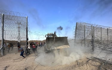 GAZA CITY, GAZA - OCTOBER 7: Palestinians groups break over a fence with the help of a digger as the clashes between Palestinian groups and Israeli forces continue in Gaza City, Gaza on October 7, 2023. (Photo by Ashraf Amra/Anadolu Agency via Getty Images)