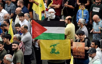 epa10907174 Supporters of Hezbollah carry Palestinian (C top) and Hezbollah (C, bottom) flags during a rally to express solidarity with Palestinians in the Gaza Strip, in Beirut, Lebanon, 08 October 2023. Rocket barrages were launched from the Gaza Strip early 07 October in a surprise attack on Israel claimed by the Islamist movement Hamas.  EPA/WAEL HAMZEH