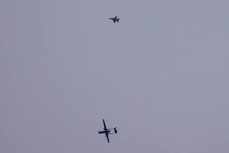 An Israeli unmanned aerial vehicle (UAV or drone) and a fighter jet (top) fly over the border with the Gaza Strip in southern Israel on November 17, 2023 amid the ongoing battles between Israel and the Palestinian group Hamas in the Gaza Strip. (Photo by JACK GUEZ / AFP)