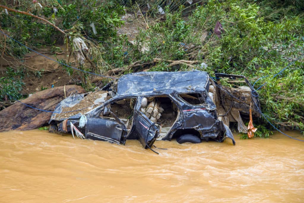 I resti di un'auto travolta da un'inondazione improvvisa sulla riva di un fiume nel distretto di Pesisir Selatan