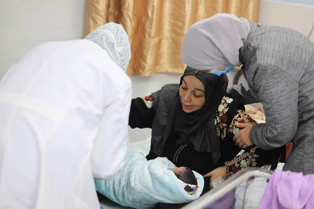 Mariam Abu Asalia, Mother of newborn is receiving assistance from MSF medical staff in the Emirati hospital.
The war in Gaza has completely disrupted access to maternity care, exposing both mothers and their children to serious and even life-threatening health risks. In the south of Gaza, in the Rafah area, the Emirati maternity hospital stands as the main facility catering to the maternal health needs of over 1.5 million displaced people. 
The Emirati hospital is now dealing with threefold the number of deliveries compared to pre-war times – while being overstretched and lacking sufficient medical supplies. Due to the overwhelming needs, women are often discharged only two hours after delivering. Those having undergone caesarian sections are discharged after only six hours, leaving them at high risk of complication of infection once having returned to their makeshift tents. MSF is supporting the hospital with medical supplies, reinforcement of medical staff, clean-up and inclusion of more beds to the maternity ward.