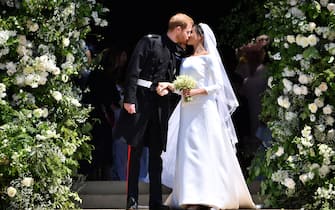 960091094 WINDSOR, UNITED KINGDOM - MAY 19: Britain's Prince Harry, Duke of Sussex kisses his wife Meghan, Duchess of Sussex as they leave from the West Door of St George's Chapel, Windsor Castle, in Windsor on May 19, 2018 in Windsor, England. (Photo by Ben STANSALL - WPA Pool/Getty Images)