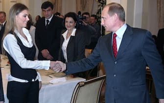 Russian President Vladimir Putin (R) shakes hands with famous Russian gymnasts Alina Kabayeva (C) and Svetlana Khorkina (L) during the meeting with sportsmen, candidates to Russian Olympic team for Olympics 2004, in the presidential residence in Novo-Ogaryovo outside Moscow, 10 March 2004. Vladimir Putin said Russian business is ready to support Russian sportsmen. AFP PHOTO / POOL        (Photo credit should read SERGEI CHIRIKOV/AFP via Getty Images)