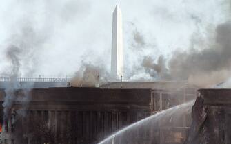 394276 01:  The Washington Momument stands in the background as firefighters pour water on a fire at the Pentagon that was caused by a hijacked plane crashing into the building September 11, 2001 in Washington, DC.  (Photo by Greg Whitesell/Getty Images)