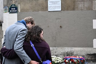 epa10972871 A couple pay their respects in front of wreaths placed next to a commemorative plaque to mark the eighth anniversary of the Paris attacks of 13 November 2015, near the 'Petit Cambodge' and 'Carillon' bar and restaurants in Paris, 13 November 2023. On 13 November 2015, gunmen killed 130 people in a terrorist attack across Parisian cafes, the Stade de France stadium and the Eagles of Death Metal concert at the Bataclan concert hall.  EPA/BERTRAND GUAY / POOL  MAXPPP OUT