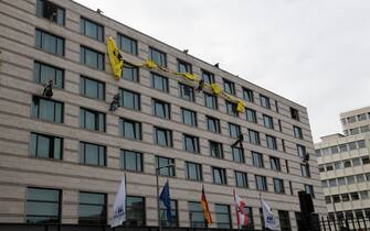 28 May 2019, Berlin: Activists of the environmental organization greenpeace rope down on the facade of a hotel and hang up a poster with the words "Rheinmetall bombs kill in Yemen". The Rheinmetall armaments group's annual general meeting is held at the hotel. Photo: Paul Zinken/dpa
