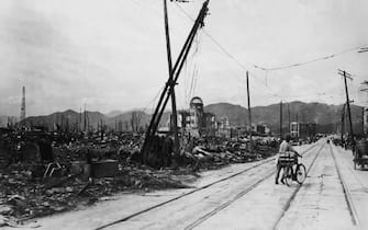 August 1945:  A man wheels his bicycle thorough Hiroshima, days after the city was leveled by an atomic bomb blast, Japan. The view here is looking west-northwest, about 550 feet from where the bomb landed, known as X, on August 6, 1945.  (Photo by Keystone/Getty Images)