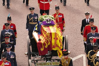 LONDON, ENGLAND - SEPTEMBER 14: The coffin of Queen Elizabeth II, draped in the Royal Standard with the Imperial State Crown placed on top, is carried on a horse-drawn gun carriage of the King's Troop Royal Horse Artillery, during the ceremonial procession from Buckingham Palace to Westminster Hall, London, where it will lie in state ahead of her funeral on Monday, on September 14, 2022 in London, England (Photo Victoria Jones - WPA Pool/Getty Images)