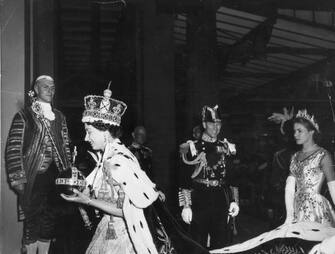 2nd June 1953:  Queen Elizabeth II, wearing the Imperial State crown and carrying the Orb and Sceptre, returns to Buckingham Palace from Westminster Abbey, London, following her Coronation.  (Photo by Topical Press Agency/Getty Images)