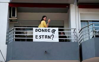 A woman smokes at a balcony next to a sign reading "Where are they?" and displaying the daisy of the Madres y Familiares de Uruguayos Detenidos Desaparecidos civil association logo, in Montevideo on May 20, 2020, within the framework of the commemoration of the Marcha del Silencio which, due to restrictions on the COVID-19 pandemic, is being held virtually through social media and street interventions. - May 20 marks the 25th anniversary of the so-called Marcha del Silencio (March of Silence), held each year to commemorate the murder of Uruguayan congressmen Zelmar Michelini and Hector Gutierrez Ruiz -killed by a military commando while in exile in Argentina during the plan Condor period- and to demand justice in the unsolved cases of missing people during the dictatorship (1973-1985). (Photo by Eitan ABRAMOVICH / AFP) (Photo by EITAN ABRAMOVICH/AFP via Getty Images)