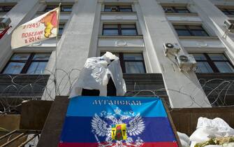 A flag (C) of the self-proclaimed "Lugansk People's Republic" hangs outside the headquarters on June 22, 2014. The flag flying at L reads: "victory in 1945, victory in 2014".  Donetsk and the neighbouring heavily Russified region of Lugansk declared independence in disputed May 11 referenda, the legitimacy of which was rejected by Kiev and the West. AFP PHOTO / JOHN MACDOUGALL        (Photo credit should read JOHN MACDOUGALL/AFP via Getty Images)