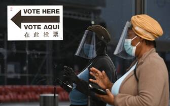 Wearing a mask and a shield, a woman gestures as she speaks on her cell phone while standing in line outside the Barclays Center on the first day of early voting for the 2020 Presidential elections, in the  New York City borough of Brooklyn, NY, October 24, 2020. In a deal reached with the NBA, sports arenas such as the Barclays Center will be used as polling sites, one of 88 early voting ballot casting sites, this the first time in history New York participates in early voting.  (Anthony Behar/Sipa USA)