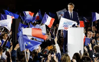 TOPSHOT - France's President and French liberal party La Republique en Marche (LREM) candidate to his succession Emmanuel Macron stands after delivering a speech on stage at a gathering with supporters waving European Union and French flags, at the place du Chateau, in Strasbourg, eastern France, on April 12, 2022, during a one-day campaign visit in the Grand-Est region. - Emmanuel Macron and his rival French far-right party Rassemblement National (RN) presidential candidate have kicked off a final fortnight of bruising campaigning for the French presidency in a run-off that polls predict risks being tight. (Photo by Ludovic MARIN / AFP) (Photo by LUDOVIC MARIN/AFP via Getty Images)