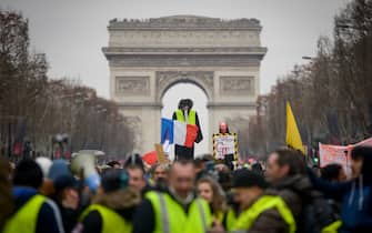 TOPSHOT - Yellow vest protestors hoist an effigy with a French national flag in front of The Arc de Triomphe on The Champs-Elysees in Paris on January 5, 2019, during a rally by yellow vest "Gilets Jaunes" anti-government protestors. - Over the past six weeks, "yellow vest" demonstrators -- so-called after the high-visibility jackets they wear -- have repeatedly clashed with police in Paris and other big cities, plunging Macron's presidency into crisis. The "yellow vest" movement began in rural France over fuel taxes and quickly ballooned into a wider revolt against the 41-year-old president's pro-business policies and perceived arrogance by low-paid workers and pensioners. (Photo by Lucas BARIOULET / AFP) (Photo by LUCAS BARIOULET/AFP via Getty Images)