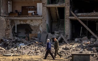 People walk past a building with a collapsed facade at the Vizar company military-industrial complex, after the site was hit by overnight Russian strikes, in the town of Vyshneve, southwestern suburbs of Kyiv, on April 15, 2022. - A Ukrainian military factory outside Kyiv that produced missiles allegedly used to hit Russia's Moskva warship was partly destroyed by overnight Russian strikes, an AFP journalist at the scene saw on April 15. A workshop and an administrative building at the Vizar plant were seriously damaged. (Photo by FADEL SENNA / AFP) (Photo by FADEL SENNA/AFP via Getty Images)