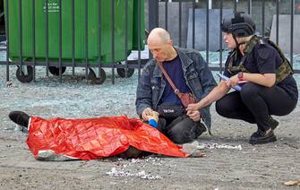 epaselect UKRAINE RUSSIA CONFLICT epaselect epa10082077 A policewoman calms a local man next to the body of a child following a Russian rocket strike hitting a bus stop in Kharkiv, Ukraine, 20 July 2022. At least three people were killed, including a 13-year-old, and two injured in the attack, according to the State Emergency Service. Kharkiv and surrounding areas have been the target of heavy shelling since February 2022, when Russian troops entered Ukraine starting a conflict that has provoked destruction and a humanitarian crisis. EPA/SERGEY KOZLOV