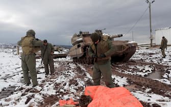 epa09706677 Israeli armored corps soldiers, fix their tank chains during snowstorm near the Israel-Syrian border in the annexed Golan Heights, near the Druze village of Majdal Shams , 24 January 2022. Media reports that for the first time Syrian and Russian military jets, including fighter, fighter-bomber, and early warning and control aircraft jointly patrolled the airspace along Syria's borders including the Golan Heights.  EPA/ATEF SAFADI
