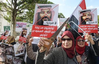 Tunisian women hold up saws and signs showing pictures of Saudi Crown Prince Mohammed bin Salman with a caption below reading in Arabic "no welcome, Tunisians against the visit of the Saudi Crown Prince to Tunisia", during an anti-Saudi Crown Prince protest in Habib Bourguiba Avenue in the capital Tunis on November 27, 2018. (Photo by FETHI BELAID / AFP)        (Photo credit should read FETHI BELAID/AFP via Getty Images)