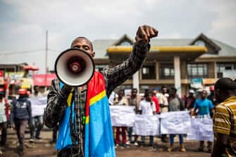 A supporter of Democratic Republic of Congo's citizen movement LUCHA (Fight For Change - Lutte Pour Le Changement) gestures as he speaks in a loud hailer during a demonstration at the Virunga Market in Goma, North Kivu, on December 21, 2018, after the Independent National Election Commission (CENI) postponed the elections until December 30. - DR Congo's troubled journey to elect a successor to the incumbent president hit a fresh snag on December 20, 2018 three days before voting, as electoral supervisors ordered a week-long postponement after a fire destroyed polling equipment. (Photo by PATRICK MEINHARDT / AFP)        (Photo credit should read PATRICK MEINHARDT/AFP via Getty Images)