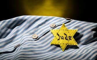 Prisoner uniform and Jewish badge on dark background, closeup. International Holocaust Remembrance Day