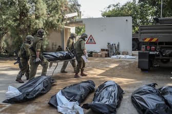 Soldati israeliani trasportano i corpi dei civili uccisi da Hamas nel kibbutz di Kfar Aza