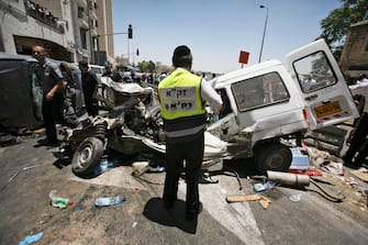 A ZAKA rescue and recovery volunteer stands next to destroyed cars at the scene of an attack in Jerusalem, Wednesday, July 2, 2008. A Palestinian driving an enormous construction vehicle went on a deadly rampage on a busy Jerusalem street Wednesday, plowing into a string of cars, buses and pedestrians, killing at least three people and wounding at least 45 before he was shot dead by security officers. The violence, the first major attack in Jerusalem since March, wreaked havoc and left a large swath of damage in the heart of downtown Jerusalem. Traffic was halted, and hundreds of people fled through the streets in panic as medics treated the wounded. (AP Photo/Dan Balilty)