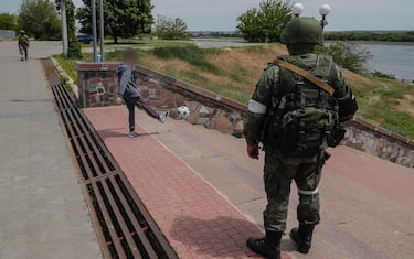 A picture taken during a media tour organized by the Russian Army shows a Russian serviceman standing guard as a boy plays with a ball on a promenade along the Dnipro River in Kherson, Ukraine, 20 May 2022 (issued 21 May 2022). The Russian-appointed head of Ukraine's Kherson region, Volodymyr Saldo, said that the area will Â?soon become part of the Russian FederationÂ?. The governor was installed by Russian forces after they took control of the southern Ukrainian region in March 2022.  ANSA/SERGEI ILNITSKY