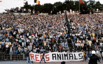 459825004 Belgium policemen face Italian fans holding a banner where is written "Reds animals", on May 29, 1985 in Heysel stadium in Brussels, as violence has broken out one hour before the European Champion Clubs final between Britain's Liverpool and Italy's Juventus of Turin, killing 39 fans and injuring more than 600. The tragedy occured when a wall collapsed in the stadium under the pressure of people and crushed Juventus fans as they tried to escape Liverpool supporters. (Photo credit should read DOMINIQUE FAGET/AFP via Getty Images)