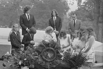 (Original Caption) Ethel Kennedy, widow of Senator Robert F. Kennedy and members of the family visited the gravesite of the late Senator at nearby Arlington National Cemetery, here. This was the third anniversary of the assassination of senator Kennedy. Left to right at gravesite are David Anthony Kennedy, Victoria Lawford, (niece of Mrs. Kennedy), Michael Lemoyne Kennedy, Joseph P. Kennedy, Jr., (standing), Mrs. Kennedy, Robert F. Kennedy Jr., (standing), Mary Courtney Kennedy, Mary Kerry Kennedy, Caroline Kennedy, (daughter of late President Kennedy), and Sydney Lawford, (niece of Mrs. Kennedy.) The man standing to the far right is Dave Hackett, a friend of the Kennedy family.