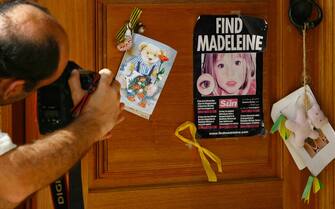 LAGOS, PORTUGAL - AUGUST 10:  A photographer takes a photograph of a poster and cards placed on the Church door in Praia da Luz for missing Madeleine McCann August 10, 2007 in Praia da Luz, Portugal. Police are continuing  their investigations in the Algarve village after blood was found in the McCann Apartment.  (Photo by Jeff J Mitchell/Getty Images)