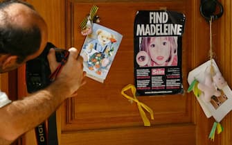 76049334 LAGOS, PORTUGAL - AUGUST 10: A photographer takes a photograph of a poster and cards placed on the Church door in Praia da Luz for missing Madeleine McCann August 10, 2007 in Praia da Luz, Portugal. Police are continuing their investigations in the Algarve village after blood was found in the McCann Apartment. (Photo by Jeff J Mitchell/Getty Images)