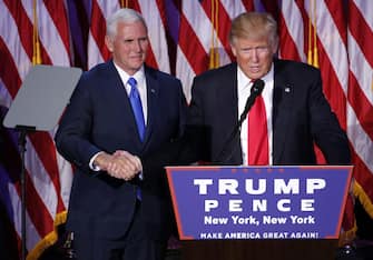 epa05623718 US Republican presidential nominee Donald Trump (C) shakes hands with running mate Mike Pence (L) as he delivers a speech on stage at Donald Trump's 2016 US presidential Election Night event as votes continue to be counted at the New York Hilton Midtown in New York, New York, USA, 08 November 2016.  EPA/SHAWN THEW
