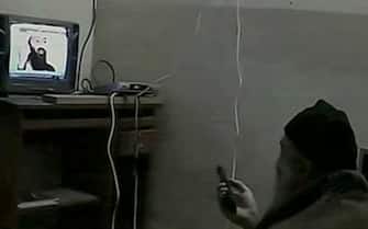 Fermoimmagine del tg3 mostra Obama bin Laden (D) con una coperta sulle spalle, un cappello e un telecomando, mentre guarda un suo filmato in cui era molto piu' giovane. E' uno dei video di Osama bin Laden sequestrati ad Abbottabad. ANSA / TG3