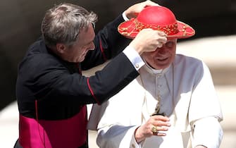 VATICAN CITY, VATICAN - JUNE 22:  Pope's personal secretary Georg Ganswein adjusts Pope Benedict XVI's 'Saturno' (pontiff's hut) as they arrive at St. Peter's square for the weekly audience on June 22, 2011 in Vatican City, Vatican. The Vatican announced yesterday that at the end of the year Pope Benedict XVI will receive a new hybrid Popemobile. (Photo by Franco Origlia/Getty Images)