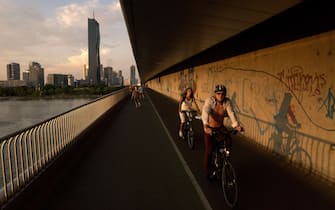 People go cycling and run on the Kaisermuhlenbrucke bridge crossing the Danube river, in late afternoon, in Vienna on August 3, 2015. AFP PHOTO/JOE KLAMARA.