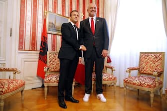 French President Emmanuel Macron (L) and Albania's Prime Minister Edi Rama wearing sneakers shake hands ahead of a meeting on the sidelines of the Western Balkans summit at the Palazzo del Governo in Trieste, northern Italy, on July 12, 2017.  / AFP PHOTO / Marco BERTORELLO        (Photo credit should read MARCO BERTORELLO/AFP via Getty Images)