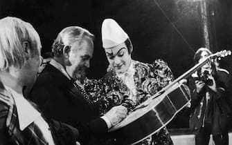 Prince Rainier of Monaco pays a visit to the Knie Circus in Vevey, 15th October 1974. After the show, he signs his autograph on a guitar belonging to the clown Rivel. (Photo by Central Press/Hulton Archive/Getty Images)