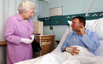 Britain's Queen Elizabeth II meets Bruce Lait, 32, a professional dancer from Ipswich at the Royal London Hospital in London's east end, 08 July 2005. Lait was on the tube train travelling between Aldgate Station and Liverpool Street Station yesterday morning, when a bomb exploded. He is explaining to the Queen how the hearing in his left ear was damaged by the blast. He was travelling to London to rehearse for a show he was scheduled to appear in with dance partner Crystal Main. The bomb attacks in London that killed at least 50 people and injured hundreds bore all the hallmarks of the Al-Qaeda network, Scotland Yard chief Ian Blair said on Friday.   AFP PHOTO /  Fiona Hanson / PA / WPA POOL (Photo credit should read FIONA HANSON/AFP via Getty Images)