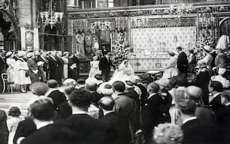 (Original Caption) 5/6/1960-The scene in Westminister Abbey this morning as Princess Margaret curtsies before H.M. the Queen while standing with her husband-who bows-after signing the marriage register. On left can be seen among others-the groom's mother Countess of Rosse-his father Mr. Ronald Armstrong Jones-while on right with the Queen the Duke of Edinburgh-Queen of Denmark and the Duchess of Kent. Chief bridesmaid Princess Anne can be seen behind Princess Margaret.