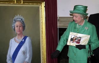 Queen Elizabeth II unveils a portrait of herself by artist Theodore Ramos at the Guildhall in Windsor, 03 June 2002, to mark her Golden Jubilee. A 1954 painting of the Queen hangs on the wall in the background.   (Photo credit should read MARTIN HAYHOW/AFP via Getty Images)