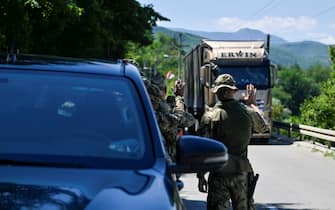 NATO soldiers greet a truck driver near the town of Zubin Potok on August 1, 2022. - Serbs in North Kosovo removed barricades on August 1 that closed two crossings along the border with Serbia after authorities in Pristina postponed the implementation of new travel measures that sparked tensions. Trucks and barriers were being cleared from the roads, according to an AFP reporter, hours after a string of shootings and air raid sirens in northern Kosovo sent tensions soaring in the disputed territory home to both Serbs and ethnic Albanians. (Photo by Armend NIMANI / AFP) (Photo by ARMEND NIMANI/AFP via Getty Images)